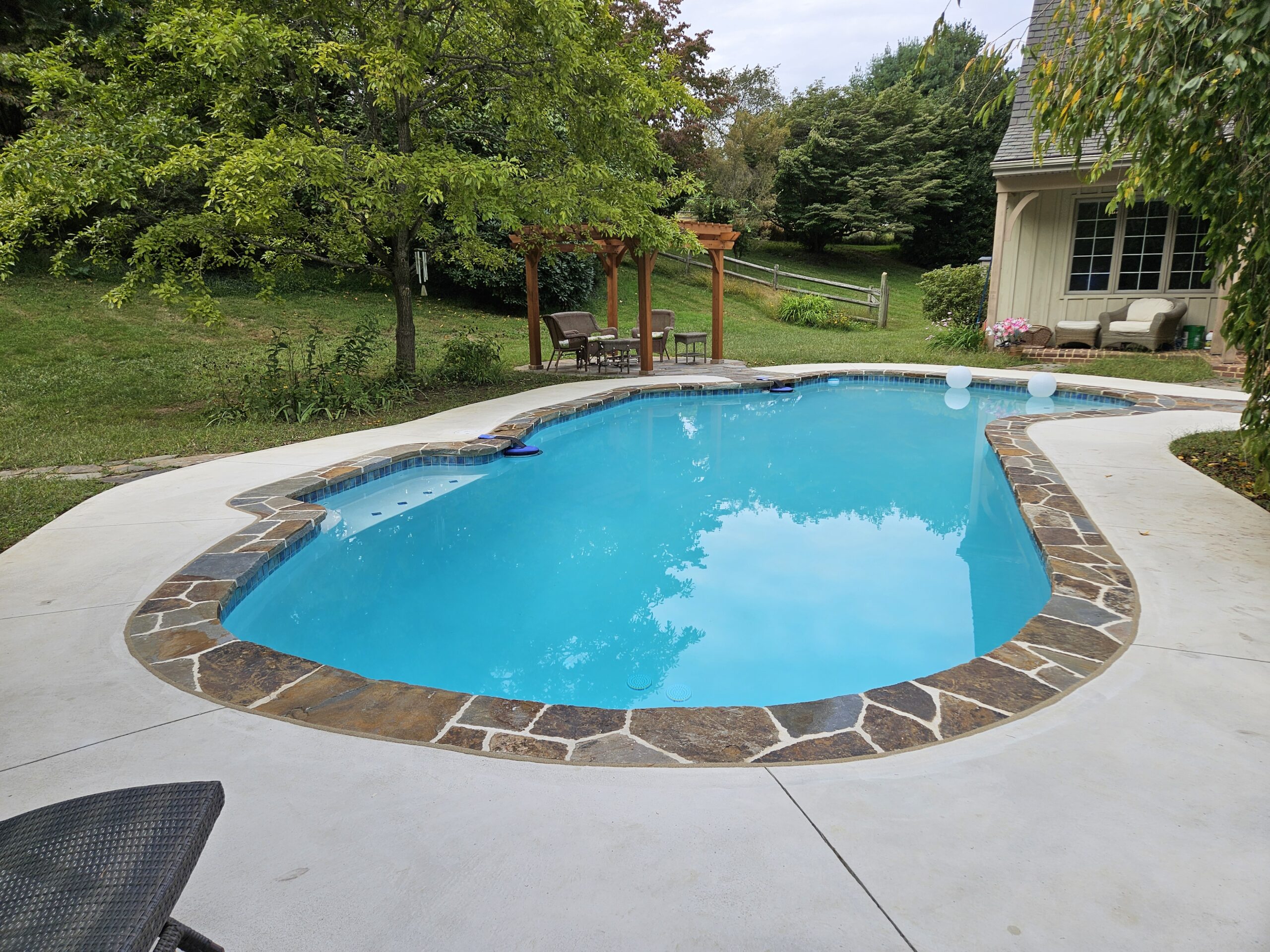 Unionville pa pool renovation with custom concrete deck and stone patios